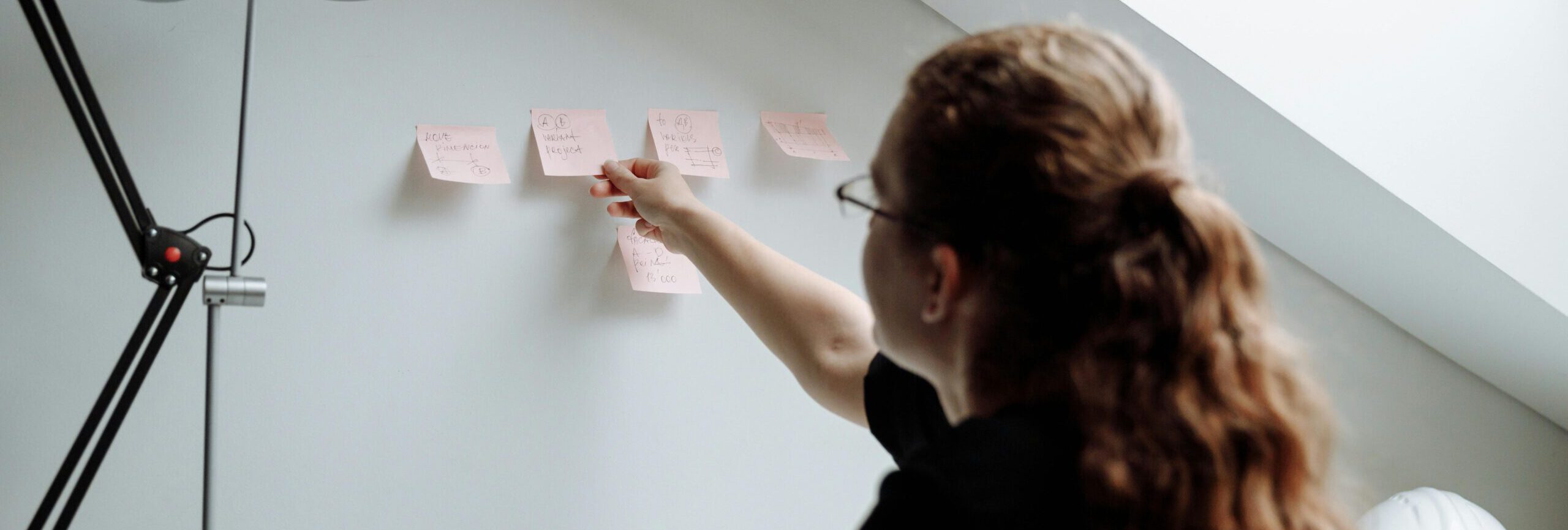 Frau hängt Notizzettel an die Wand für mehr Produktivität.