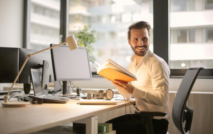 Mitarbeitermotivation: Ein erfreuter Mitarbeiter sitzt am Tisch.