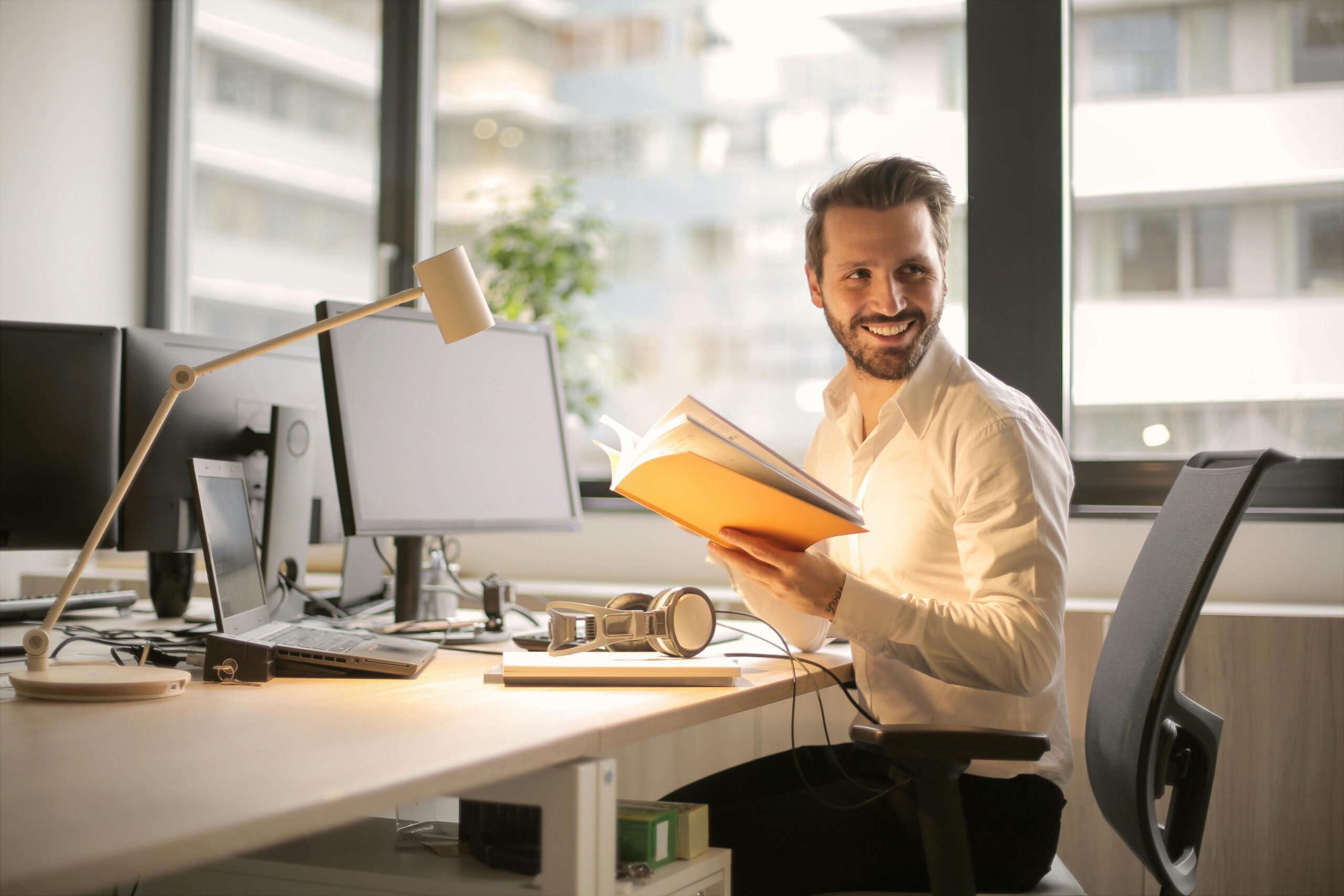 Mitarbeitermotivation: Ein erfreuter Mitarbeiter sitzt am Tisch.